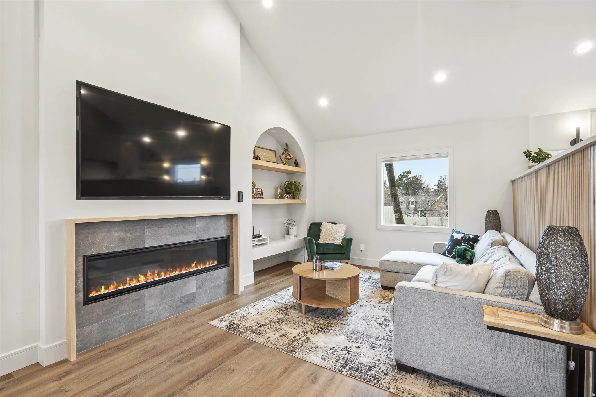Living area featuring built in features, light wood-type flooring, a fireplace, recessed lighting, and high vaulted ceiling