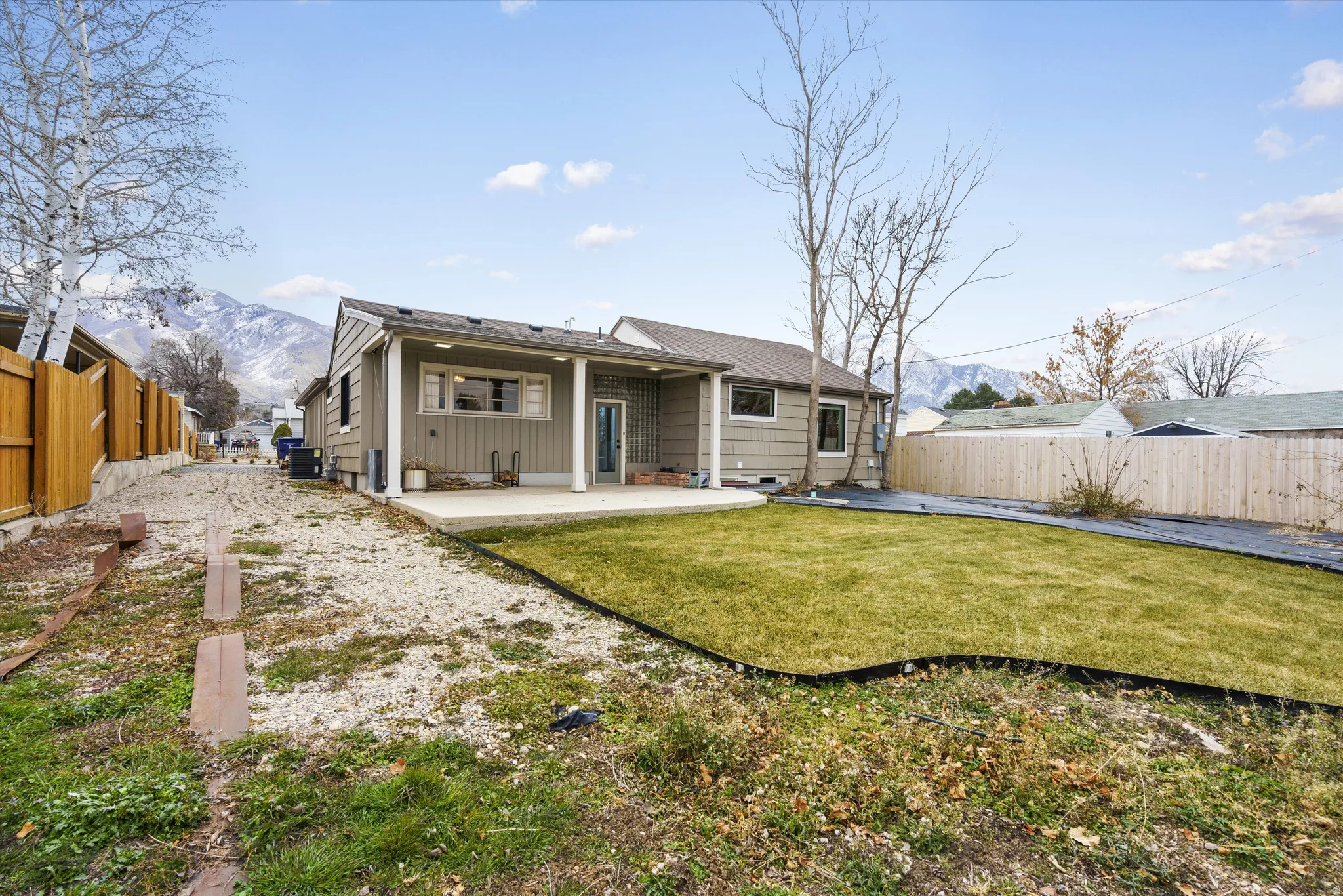 Back of house with a mountain view, a patio area, a fenced backyard, and a shingled roof