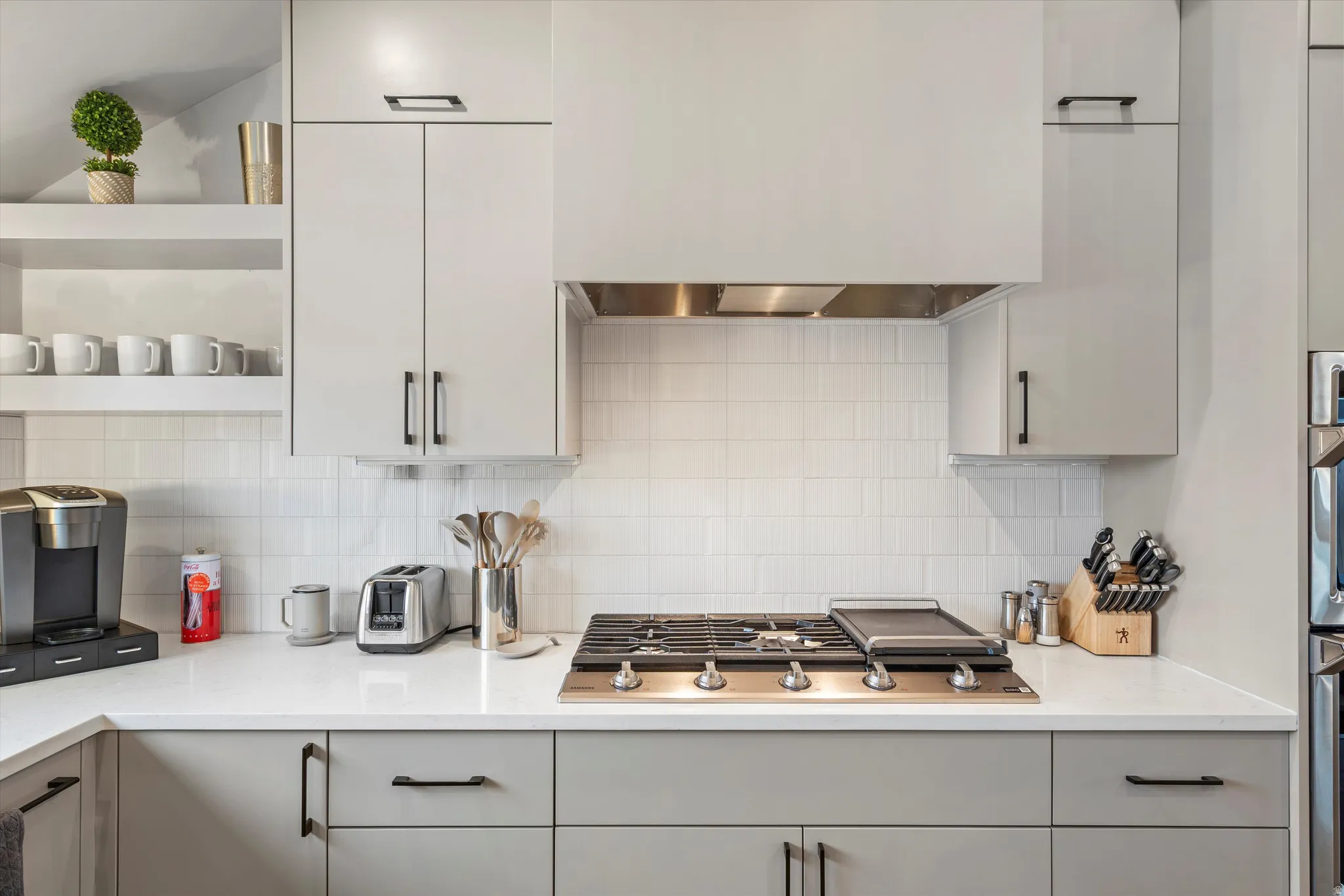 Kitchen with open shelves, stainless steel appliances, light stone counters, and gray cabinets