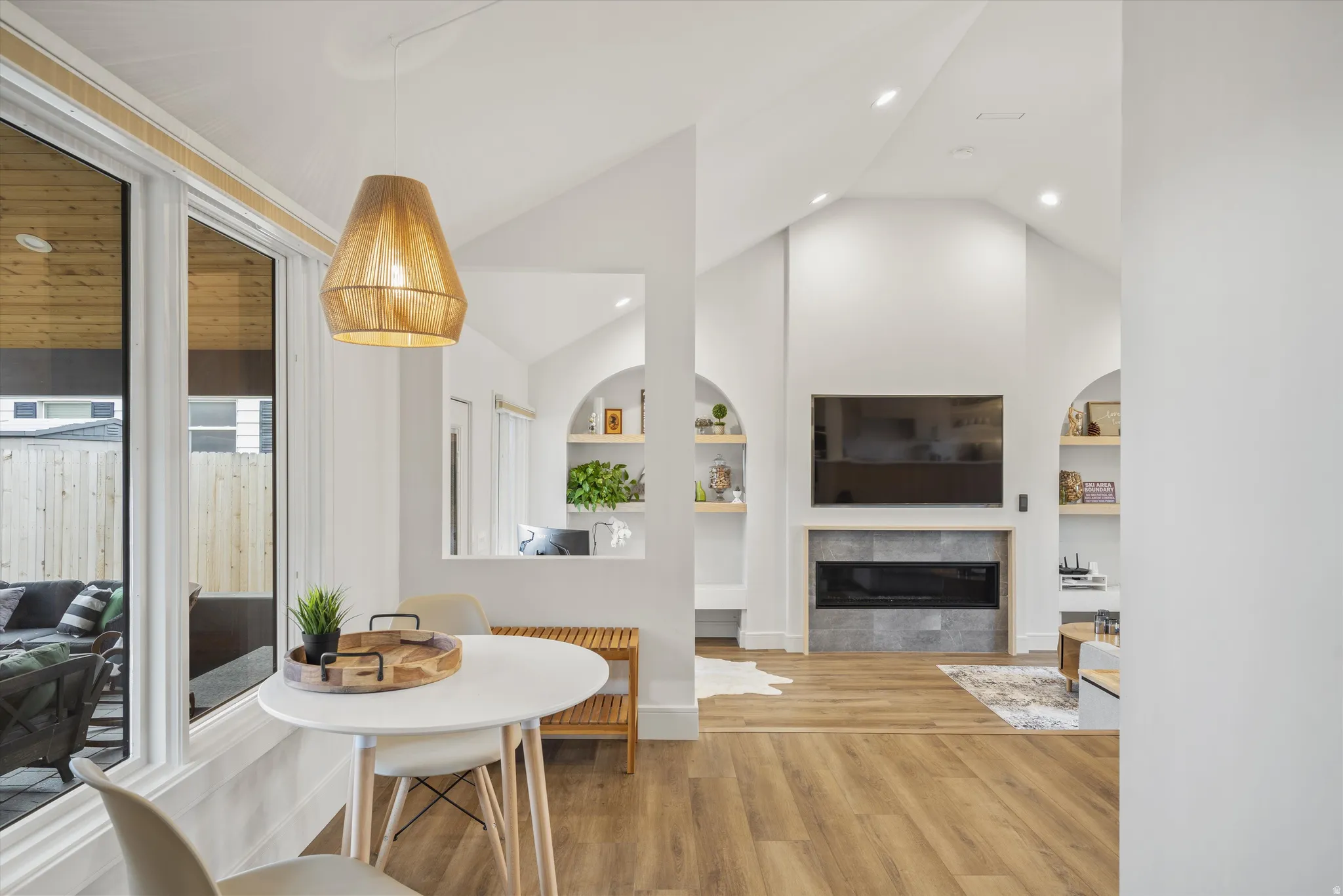 Dining area featuring built in features, lofted ceiling, light wood finished floors, a tile fireplace, and recessed lighting