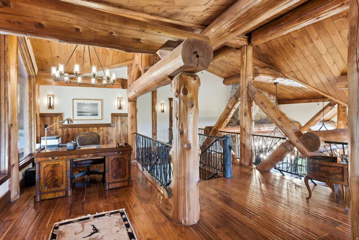 Wood-finish flooring throughout, featuring prominent exposed log beams and posts