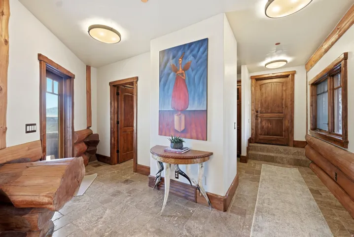 Entryway featuring wood-finish log accents, tile flooring, and rustic wood doors with matching trim
