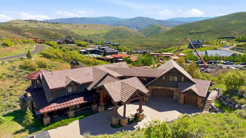 Expansive mountain-style residence featuring a multi-gabled tile roof, stone and wood-paneled exterior, and a porte-cochère entry
