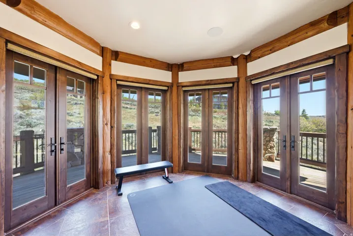 Room featuring multiple sets of French doors, log beam accents, and tile flooring
