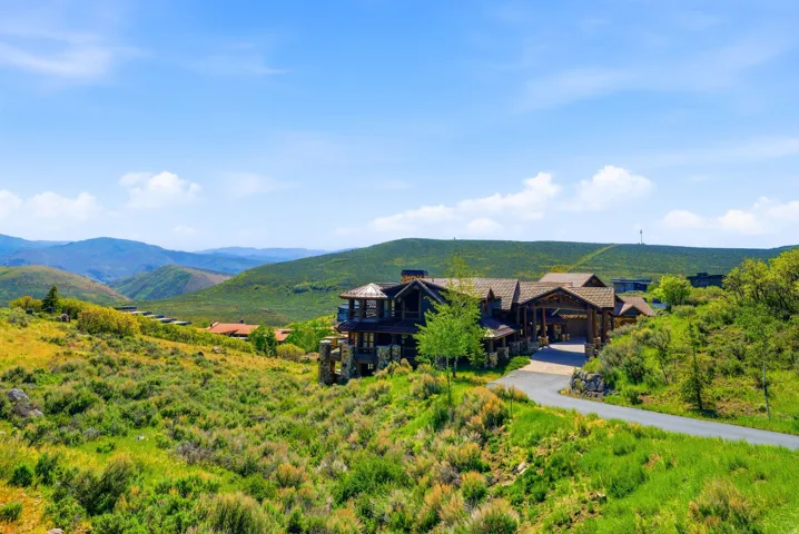 Expansive hillside property featuring a multi-level residence with dark wood siding, stone accents, and multiple balconies