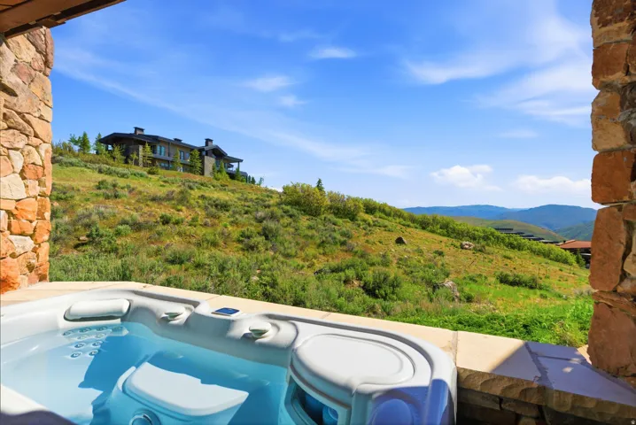Outdoor spa with stone surround, offering expansive mountain terrain scenery