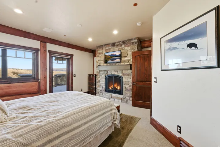 Stone-clad fireplace with a wood mantle, integrated television, and arched firebox