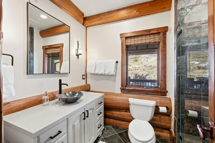 Bathroom featuring a stone vessel sink, white vanity with black hardware, and wood-finish flooring