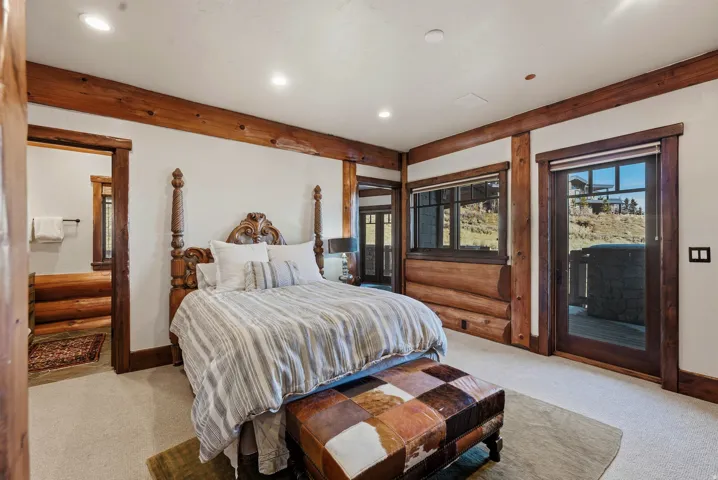 Room featuring exposed wood beams and trim, light-colored carpeting, recessed lighting, a log wall detail, and an exterior door providing direct access
