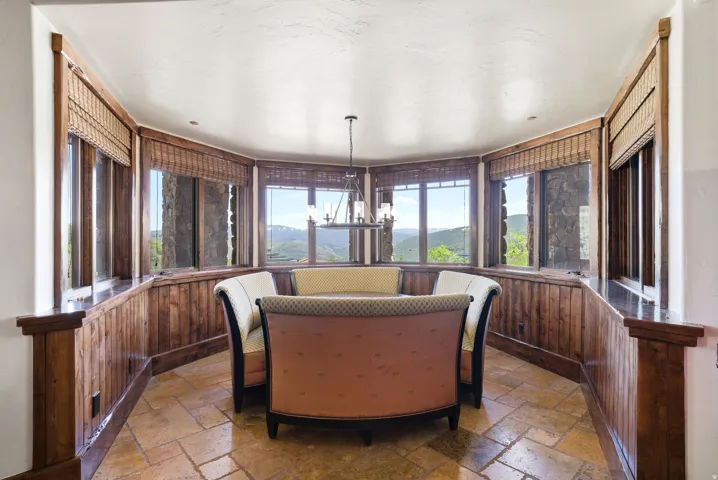Bay window dining area with natural wood paneling and stone-look flooring