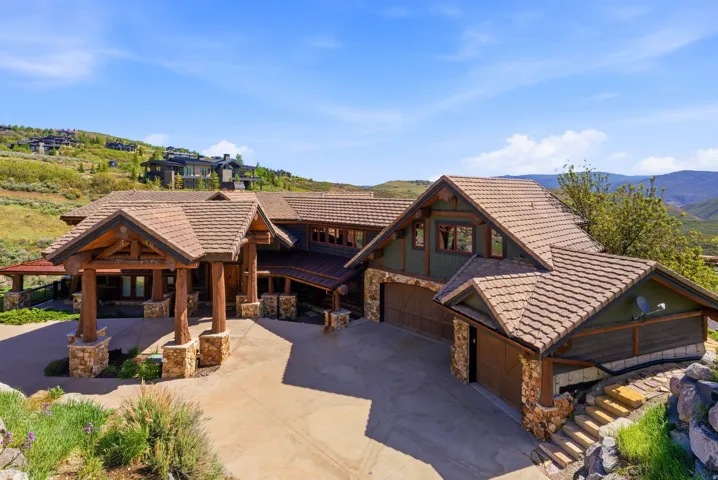 Mountain-style residence featuring a prominent portico with heavy timber framing and stone-clad columns