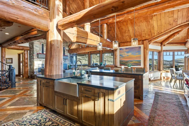 Expansive open-concept kitchen featuring a large island with a farmhouse sink and dark countertops