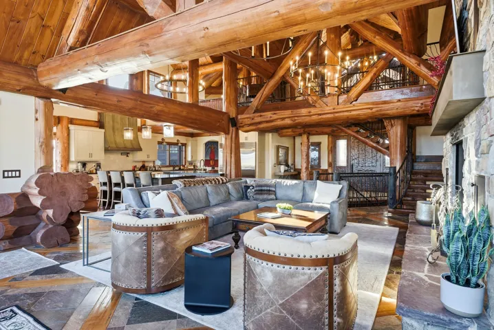 Expansive great room featuring exposed timber beams, a stone-clad fireplace, and a multi-level design