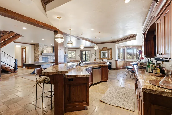 Gourmet kitchen featuring a curved multi-level island with seating, integrated stainless steel appliances, premium stone countertops, and extensive wood cabinetry