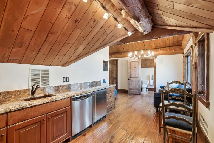 Wood-finish flooring throughout, complemented by a sloped wood-paneled ceiling with exposed wood beams