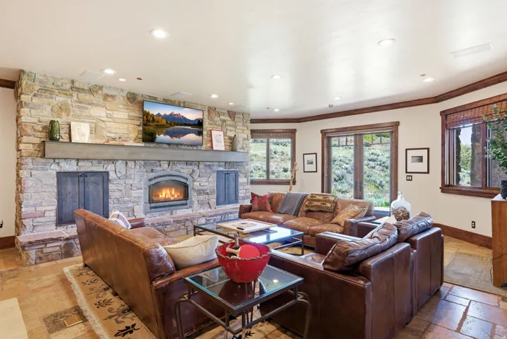Spacious living area featuring a stone-clad fireplace with a hearth, wood mantle, and integrated firebox