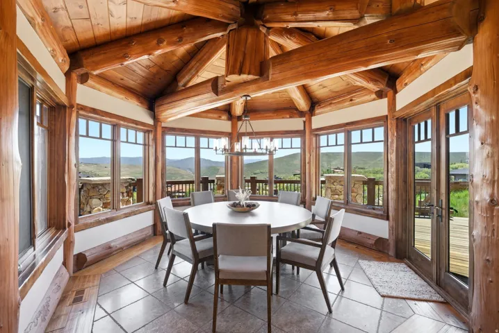 Dining area featuring exposed log beams, a vaulted wood ceiling, and multiple windows