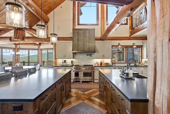Gourmet kitchen featuring a professional-grade range, custom range hood, dual kitchen islands with dark countertops, and wood-finish cabinetry