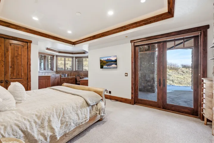 Recessed lighting illuminates a carpeted room featuring a built-in office area with cabinetry and a bay window