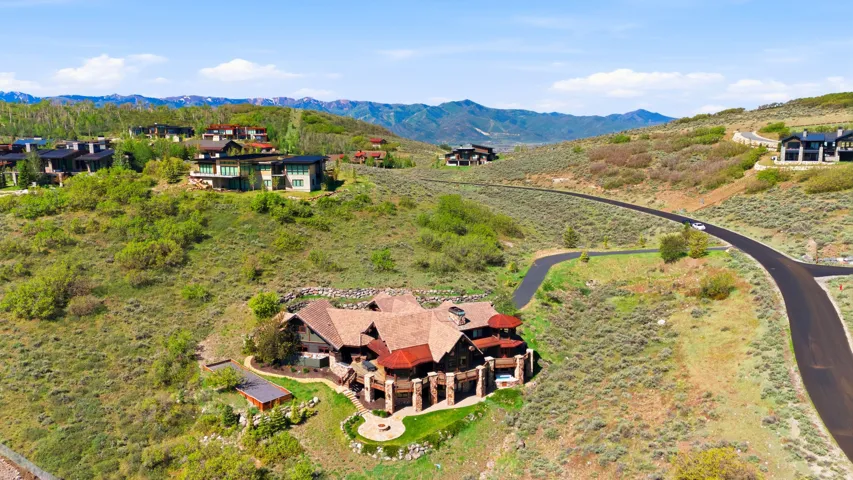 Hillside property featuring a multi-level residence with a distinct roofline, stone and wood exterior accents, and multiple outdoor patio spaces