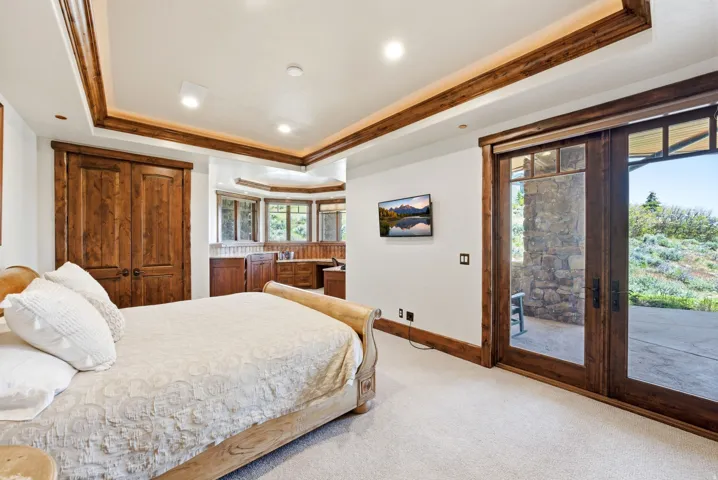 Carpeted room featuring a wood-finish bed frame, recessed lighting, and a tray ceiling with wood-finish trim