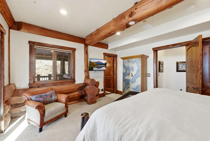 Room featuring exposed log beam construction, log window trim, and a built-in log bench