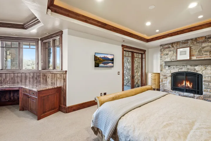 Stone fireplace with a dark metal firebox, wood mantel, and integrated lighting