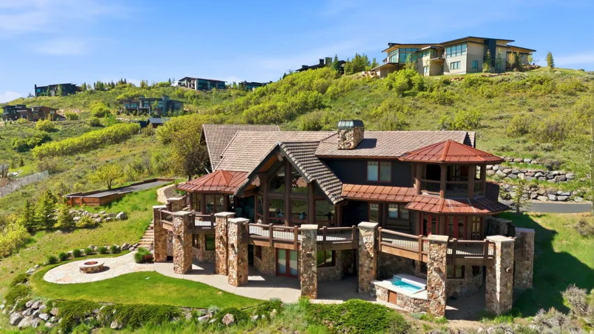 Multi-level residence featuring extensive stone work, exposed beams, and multiple outdoor deck spaces