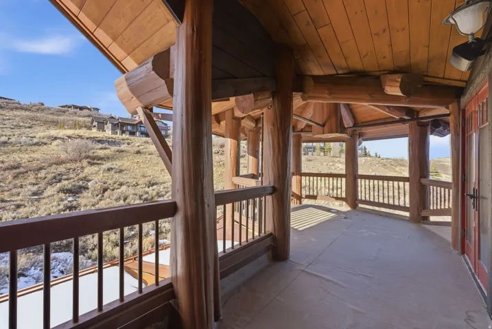 Expansive log home porch with timber beams, wood plank ceiling, and a durable concrete floor