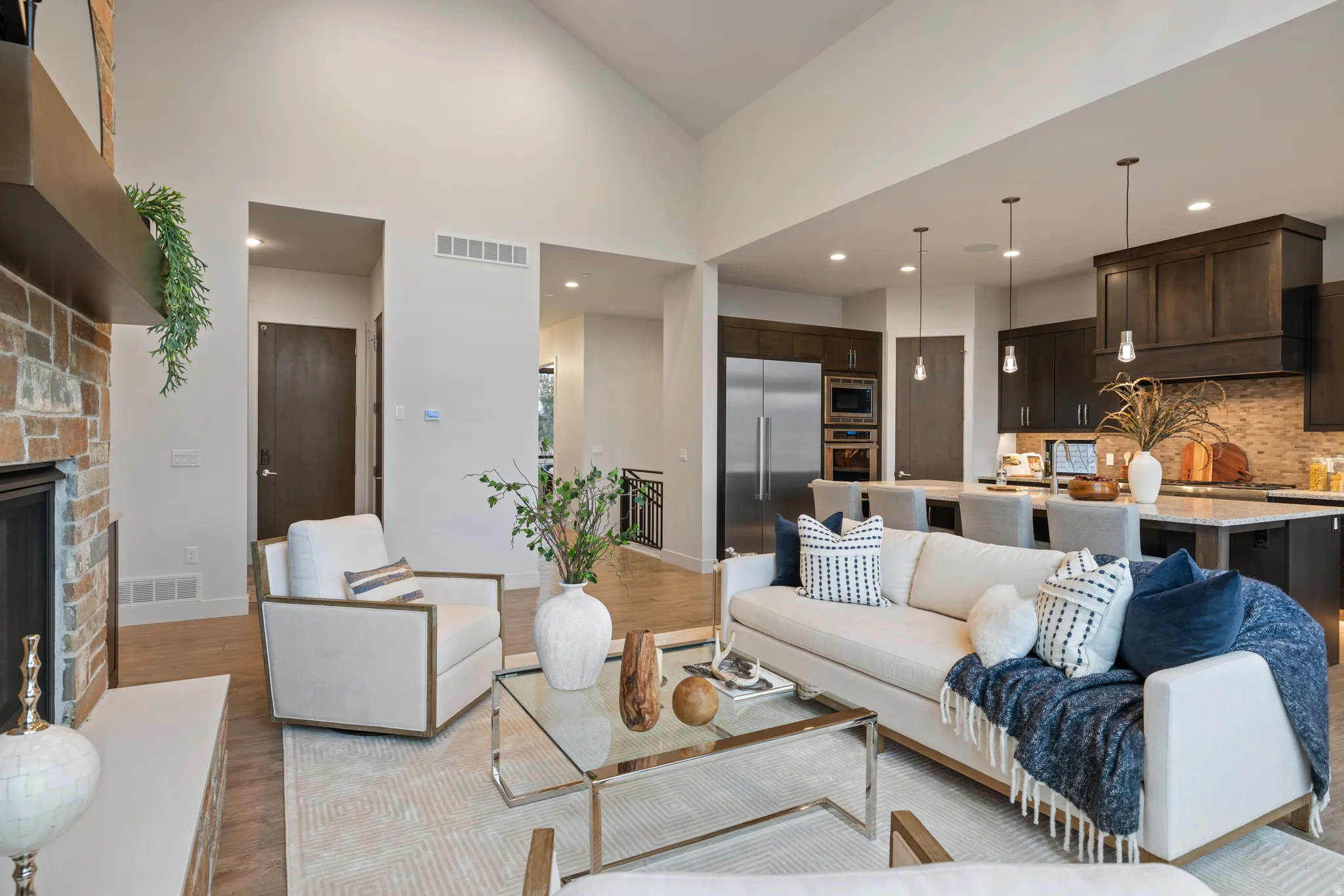 Living area with light wood-type flooring, a fireplace, recessed lighting, and a high ceiling