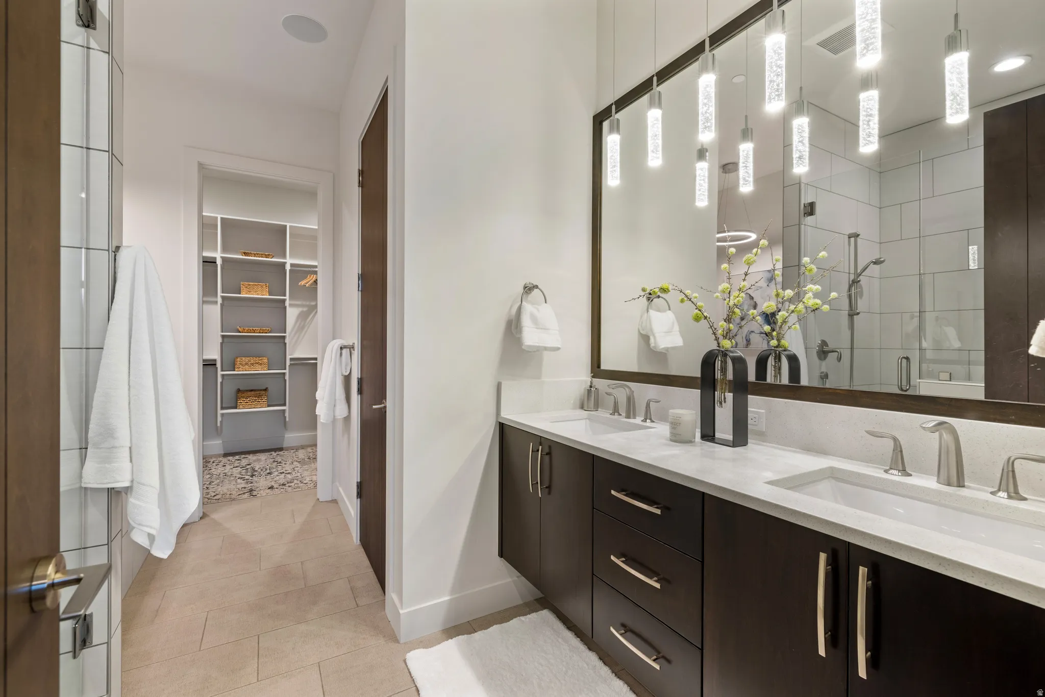 Bathroom with a spacious closet, a shower stall, double vanity, and light tile patterned flooring