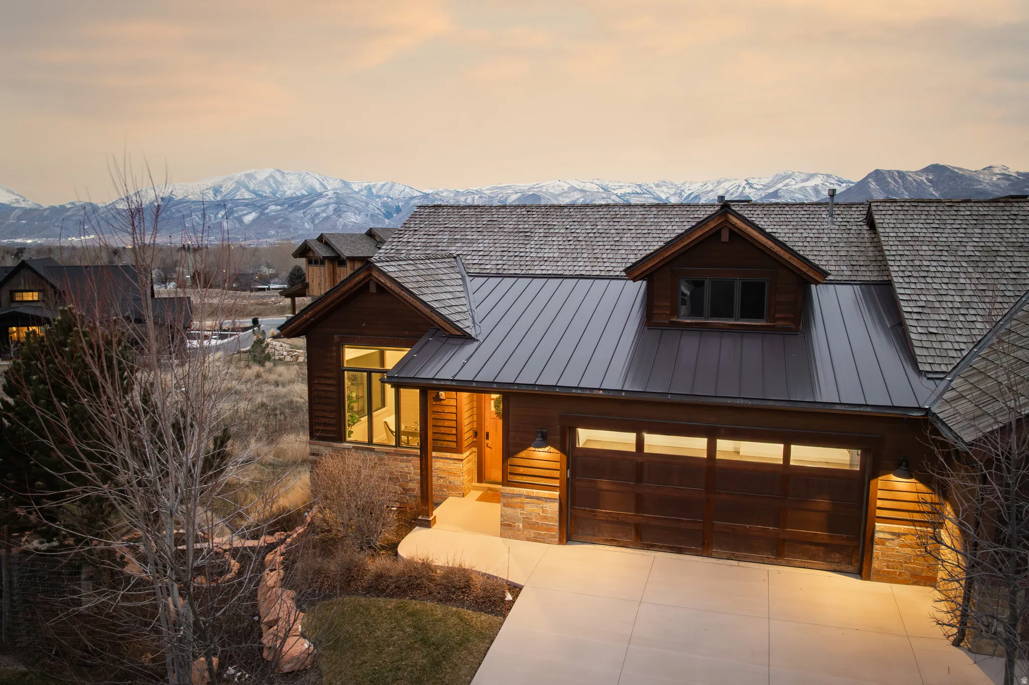 Rustic home with stone siding, a metal roof, a garage, and a mountain view
