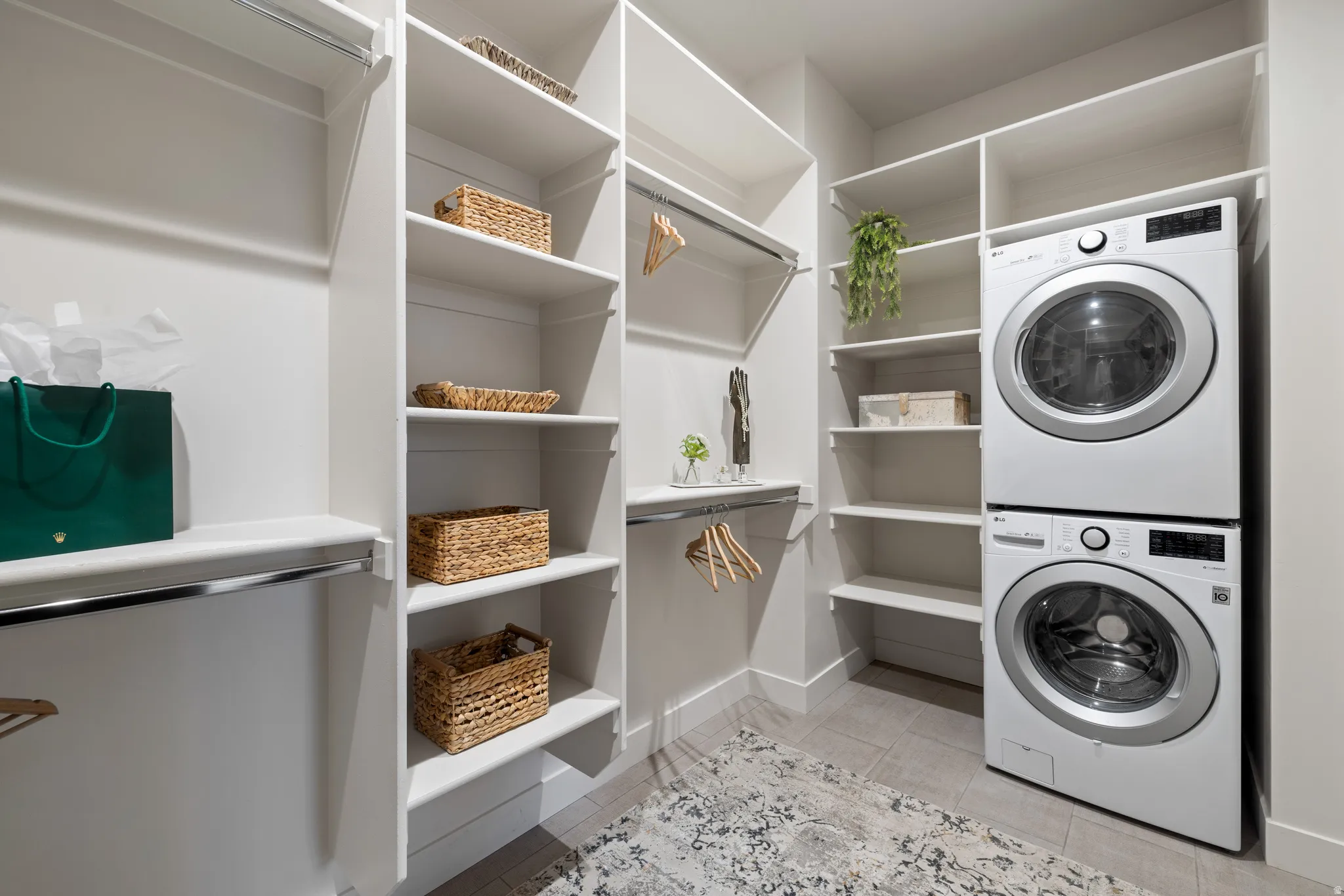 Laundry room with stacked washer / drying machine and light tile patterned floors