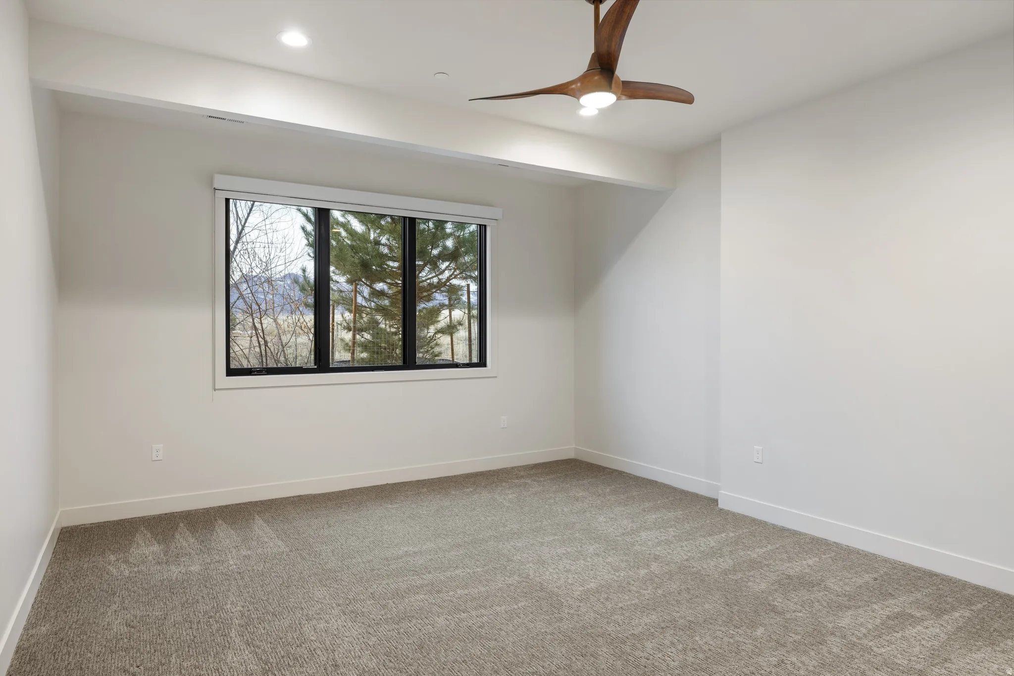 Empty room featuring light colored carpet and a ceiling fan