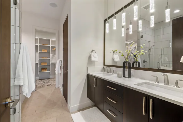 Bathroom with a spacious closet, a shower stall, double vanity, and light tile patterned flooring