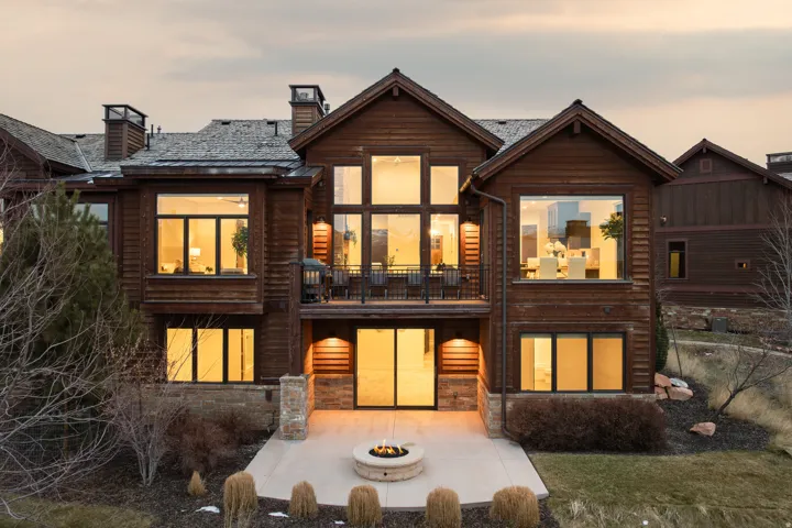 Rear view of property featuring an outdoor fire pit, a balcony, a chimney, stone siding, and a patio