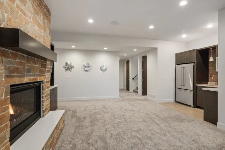 Unfurnished living room featuring light carpet, recessed lighting, a large fireplace, and stairway