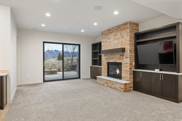 Unfurnished living room with light colored carpet, a brick fireplace, and recessed lighting