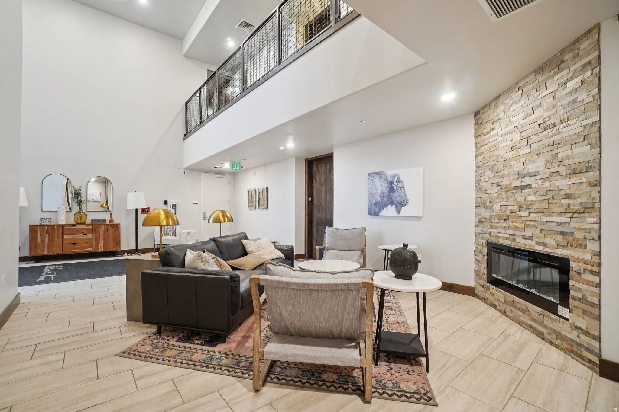Living area featuring a towering ceiling, a stone fireplace, recessed lighting, and wood finish floors