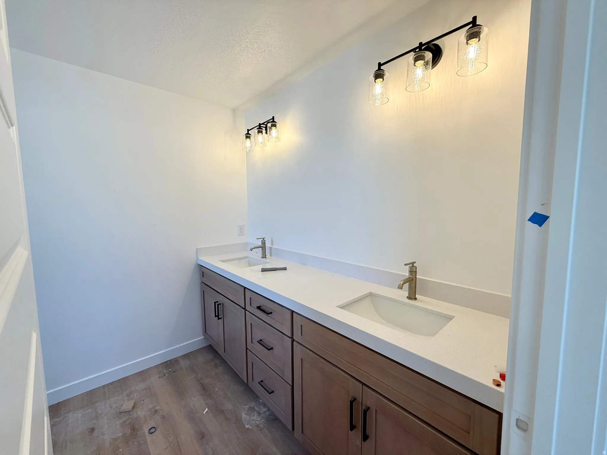 Bathroom featuring double vanity, a textured ceiling, and dark wood-type flooring
