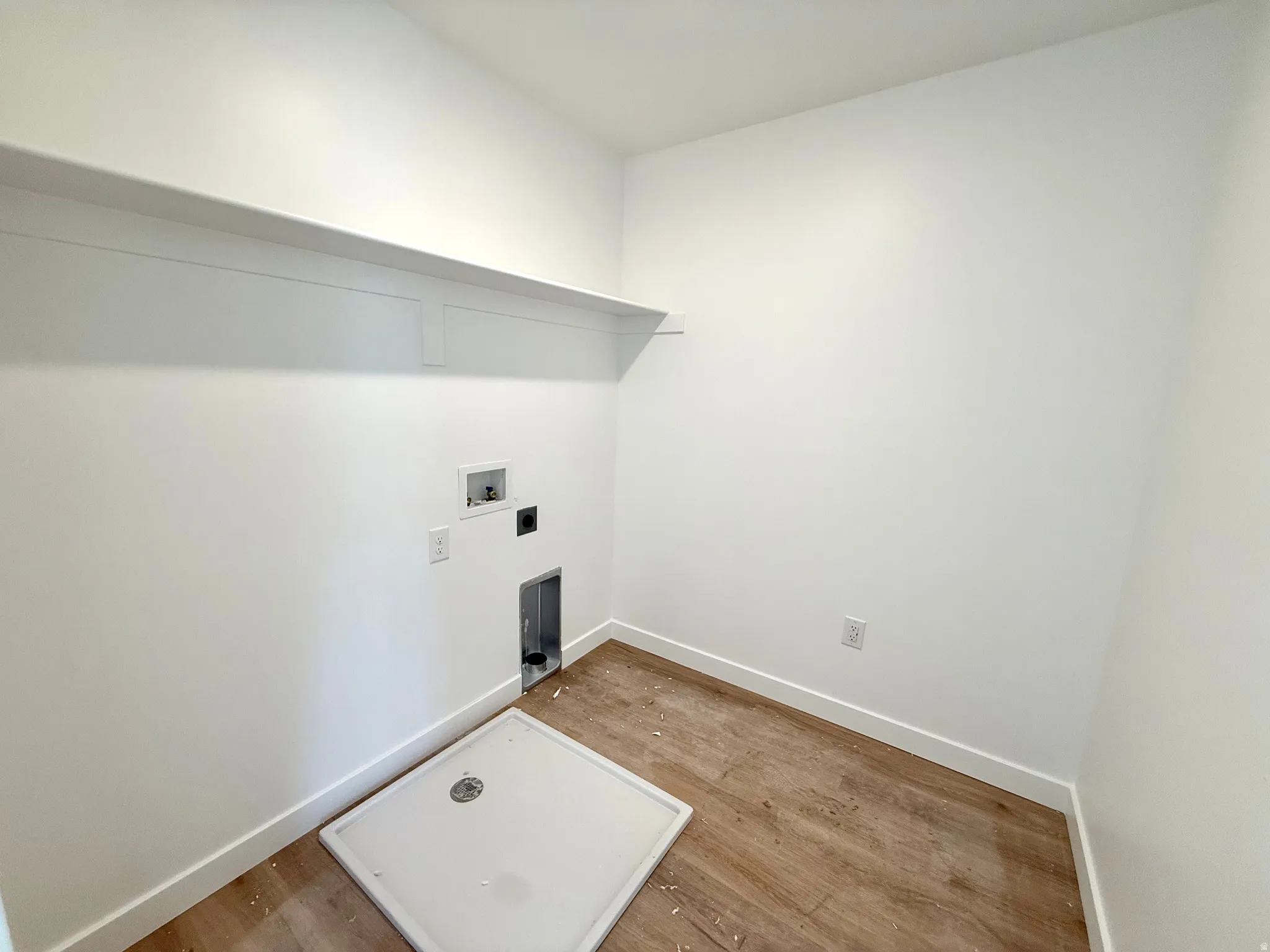 Laundry area with light wood-style flooring, hookup for a washing machine, and hookup for an electric dryer