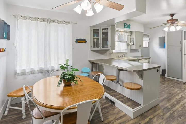 Dining space featuring a ceiling fan and dark wood-type flooring