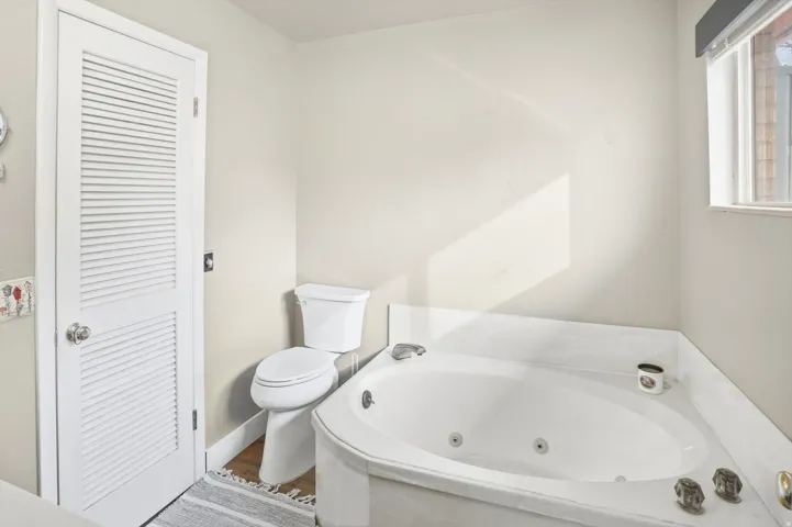Full bathroom featuring a jetted tub and toilet