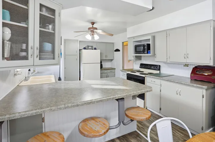 Kitchen featuring a kitchen breakfast bar, a peninsula, freestanding refrigerator, electric range, and dark wood-type flooring