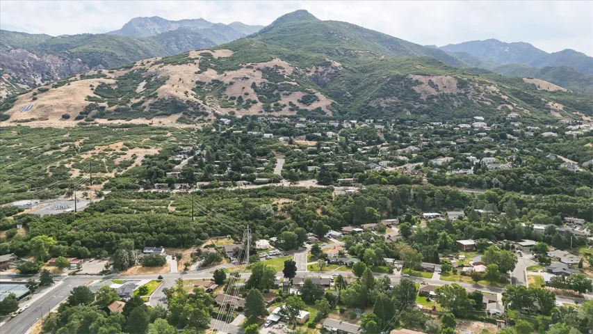Expansive aerial perspective showcasing a residential community nestled at the base of a verdant mountain range