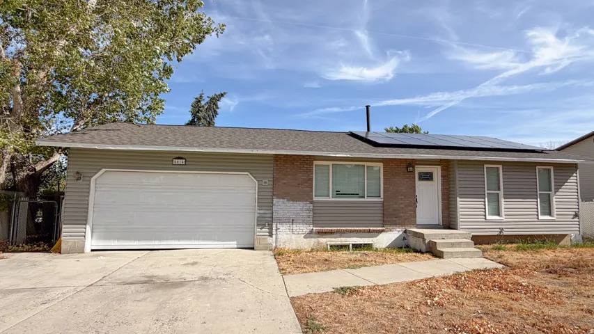 Single-story exterior with a two-car garage, front entry steps, and solar panels