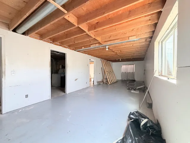 Spacious open room with exposed wood beam ceiling and natural light from multiple windows