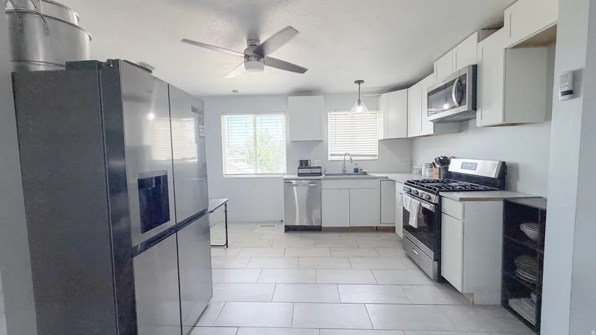 Kitchen featuring white cabinetry, stainless steel appliances, a ceiling fan, and tile flooring