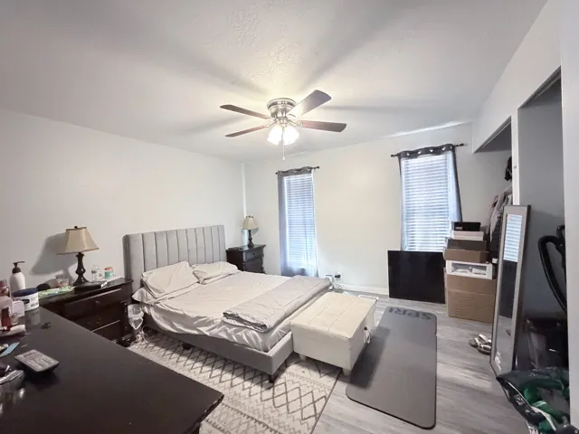 Recessed lighting, ceiling fan, two windows with blinds, and wood-finish flooring