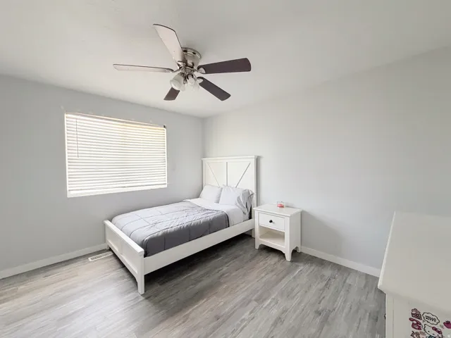 Wood-finish flooring, neutral wall tones, and a ceiling fan with integrated lighting